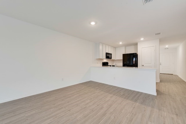 kitchen featuring visible vents, black appliances, light wood-type flooring, and baseboards