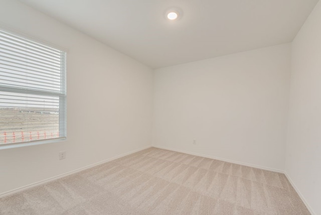 empty room featuring light carpet and baseboards