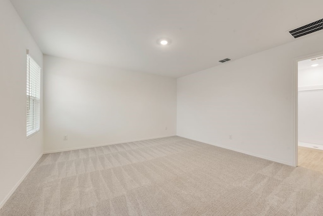 unfurnished room featuring light carpet, visible vents, and baseboards