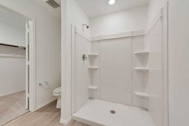 bathroom featuring wood finished floors, baseboards, visible vents, a stall shower, and toilet