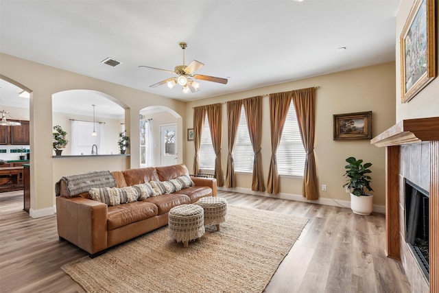 living area featuring wood finished floors, a fireplace, visible vents, and baseboards