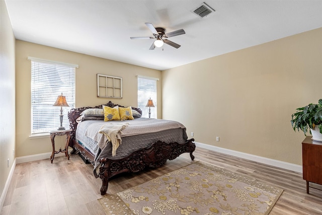 bedroom featuring ceiling fan, visible vents, baseboards, and light wood-style flooring