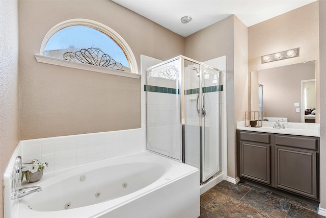 full bathroom featuring stone tile flooring, a shower stall, a jetted tub, and vanity