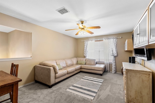 living room with visible vents, light carpet, baseboards, and a ceiling fan