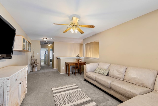 living area with baseboards, light colored carpet, and a ceiling fan