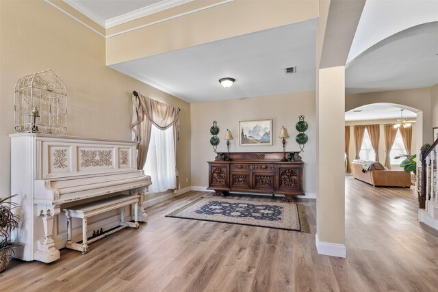 living area with wood finished floors, visible vents, baseboards, arched walkways, and crown molding