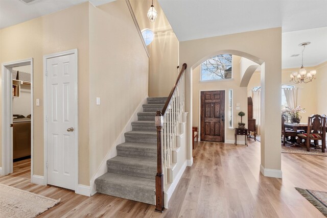 entryway featuring arched walkways, washer / clothes dryer, light wood-type flooring, and baseboards