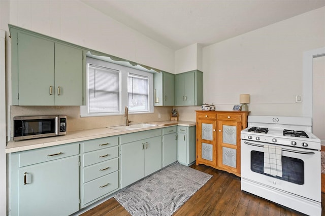 kitchen with green cabinetry, white gas stove, dark wood-style flooring, a sink, and stainless steel microwave