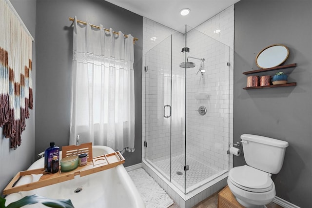 bathroom featuring toilet, baseboards, and a stall shower