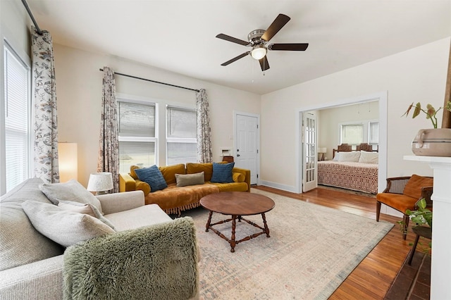 living room featuring a healthy amount of sunlight, a ceiling fan, and wood finished floors