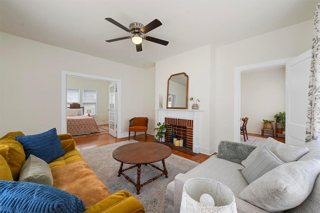 living room featuring baseboards, a ceiling fan, wood finished floors, and a fireplace