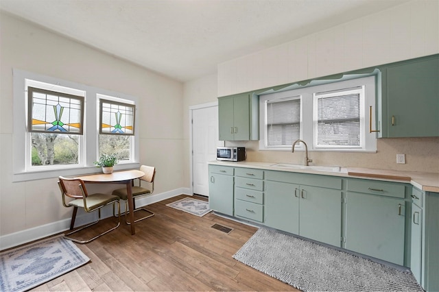 kitchen featuring a sink, visible vents, green cabinets, and light countertops