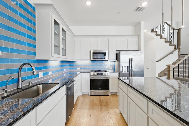 kitchen featuring visible vents, light wood finished floors, a sink, decorative backsplash, and appliances with stainless steel finishes