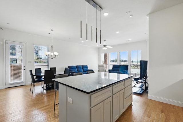 kitchen with a kitchen island, baseboards, decorative light fixtures, recessed lighting, and light wood-style flooring