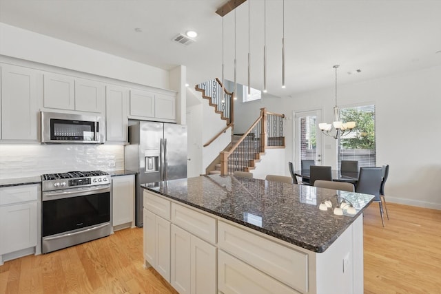 1927 Wittington Pl, Farmers Branch, TX 75234 - kitchen featuring appliances with stainless steel finishes, a chandelier, light wood finished floors, backsplash, and a kitchen island