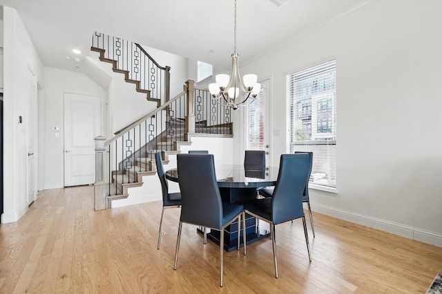 dining room with baseboards, light wood-type flooring, stairs, and an inviting chandelier