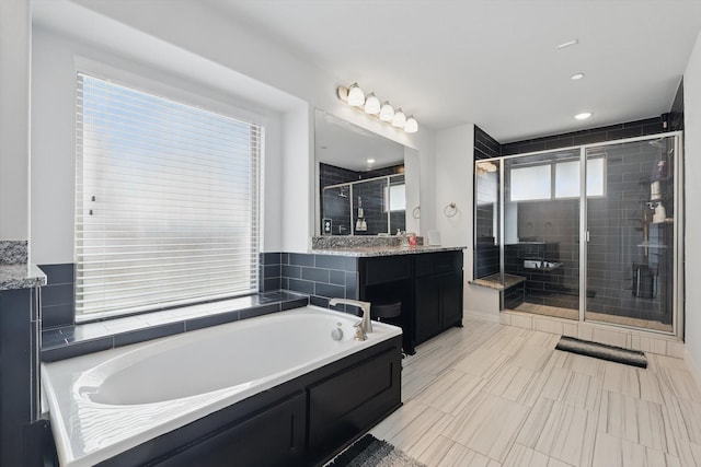 bathroom featuring a bath, a shower stall, and vanity