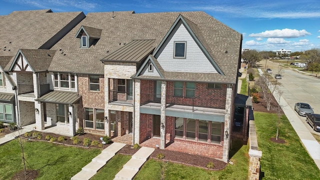 view of front of house with a standing seam roof, brick siding, roof with shingles, and metal roof