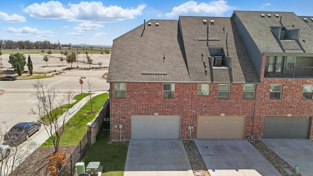 view of home's exterior featuring a garage, brick siding, driveway, and fence