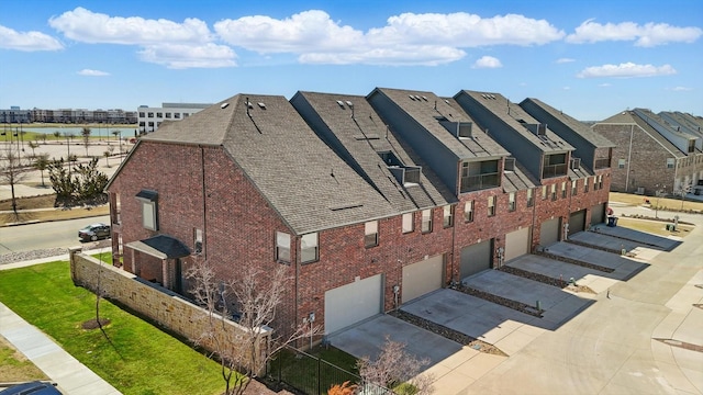 view of property exterior featuring brick siding, driveway, an attached garage, and a water view