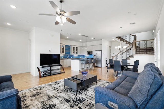 living room with a ceiling fan, visible vents, light wood finished floors, recessed lighting, and stairs