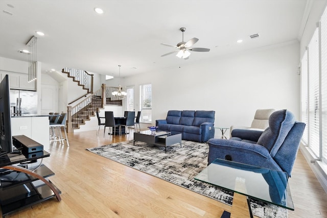 living room with stairway, visible vents, light wood-style flooring, recessed lighting, and ceiling fan with notable chandelier