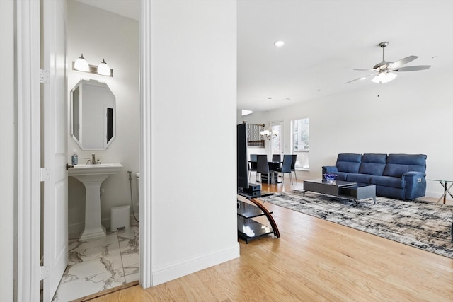 living room featuring recessed lighting, baseboards, marble finish floor, and ceiling fan with notable chandelier