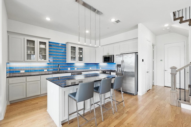 kitchen with visible vents, a breakfast bar, a sink, appliances with stainless steel finishes, and a center island