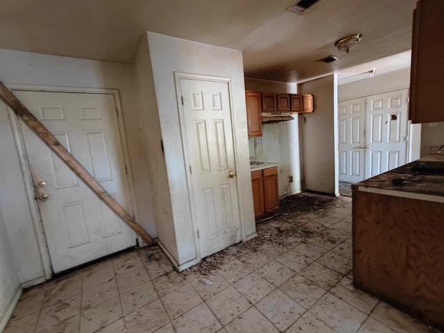 kitchen featuring brown cabinetry, visible vents, and light floors