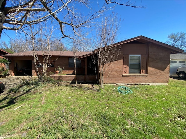 rear view of property featuring a garage, a yard, and brick siding