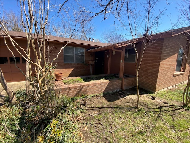 rear view of property with a garage, brick siding, and crawl space