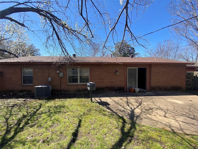 back of property with a patio area, a yard, central AC unit, and brick siding