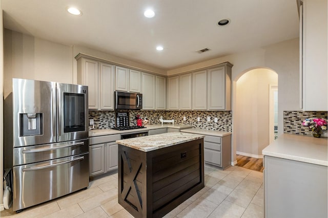 1513 Hidden Cove Ct, Allen, TX 75002 - kitchen featuring appliances with stainless steel finishes, gray cabinets, arched walkways, decorative backsplash, and light tile patterned floors