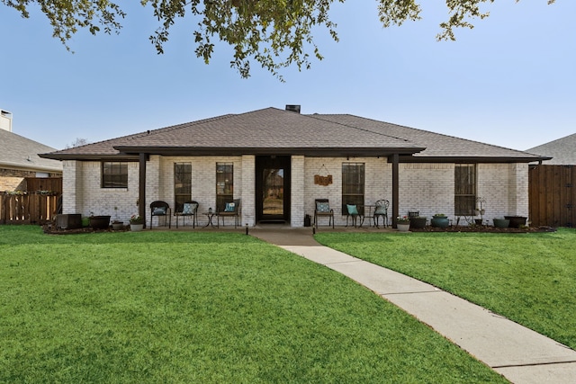 view of front of property with brick siding, a front yard, and fence