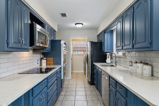 kitchen featuring blue cabinetry, stainless steel appliances, visible vents, and a sink