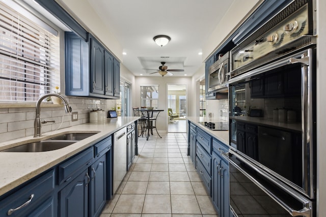 kitchen with black appliances, a ceiling fan, blue cabinetry, a sink, and light tile patterned flooring