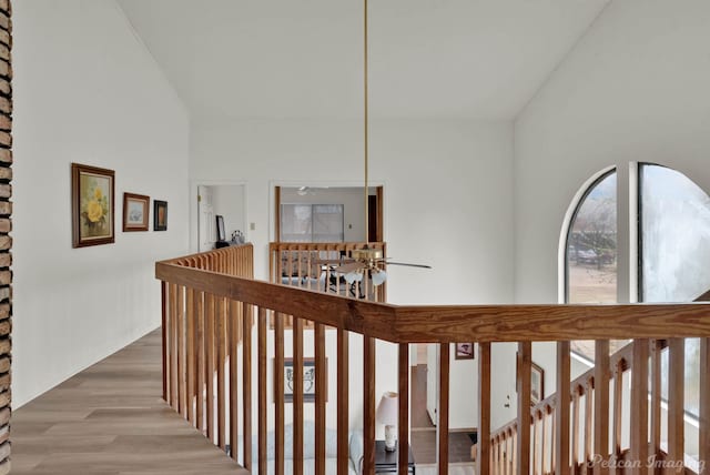 hall with high vaulted ceiling and light wood-style floors