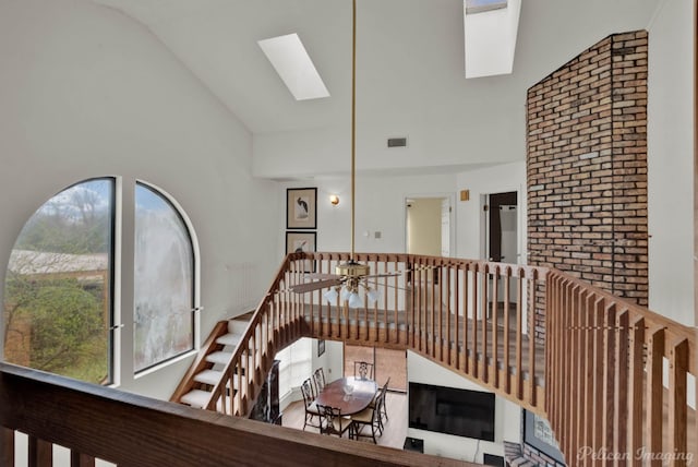 corridor featuring visible vents, plenty of natural light, a skylight, and high vaulted ceiling