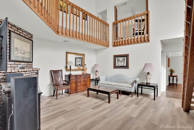 living area featuring a fireplace, a towering ceiling, and wood finished floors