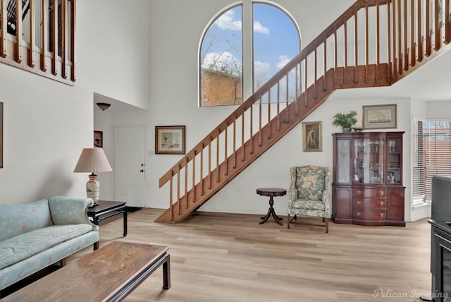 living area with a towering ceiling, wood finished floors, and stairs