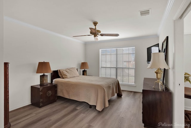 bedroom with baseboards, wood finished floors, visible vents, and ornamental molding