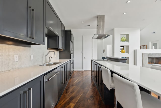 kitchen featuring backsplash, dark wood finished floors, dishwasher, island exhaust hood, and a sink