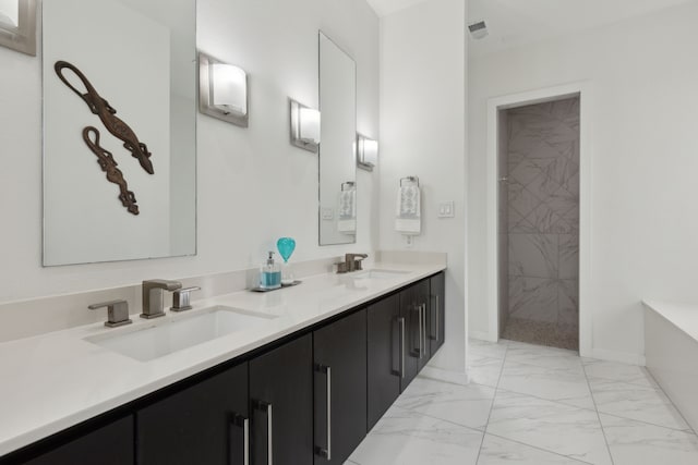 full bathroom with double vanity, tiled shower, marble finish floor, and a sink