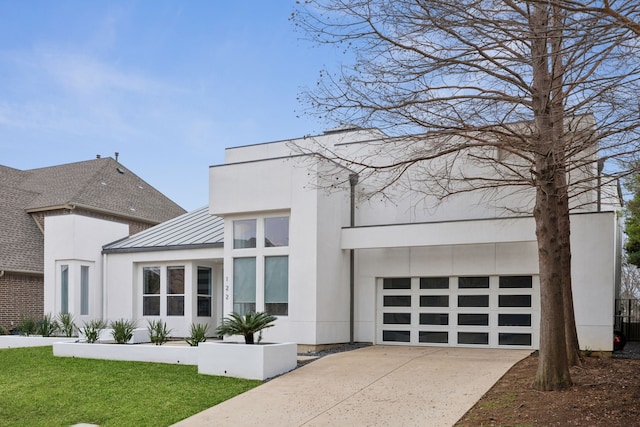 view of front of home featuring a front lawn, a standing seam roof, concrete driveway, an attached garage, and metal roof