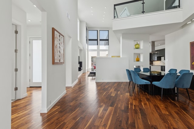 dining space featuring baseboards, a towering ceiling, and wood finished floors