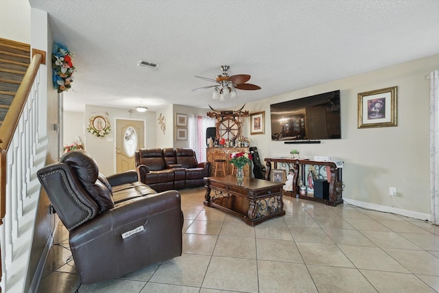 living area featuring light tile patterned floors, visible vents, a textured ceiling, and a ceiling fan