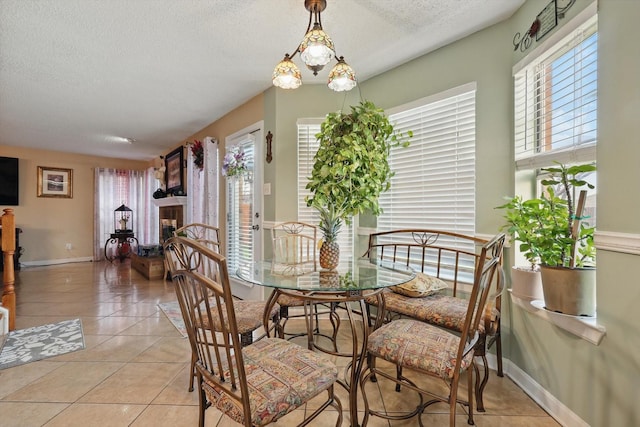 dining space featuring light tile patterned floors, baseboards, and a textured ceiling