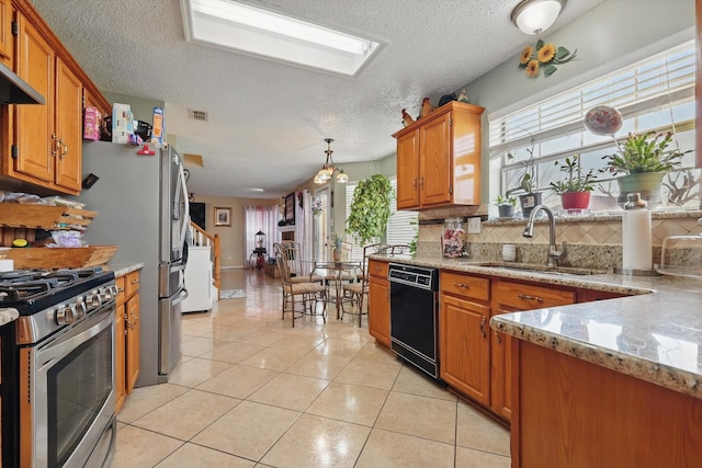 kitchen with black dishwasher, a wealth of natural light, light tile patterned flooring, stainless steel gas range, and a sink