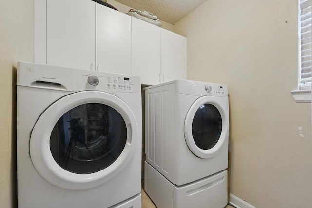 clothes washing area featuring cabinet space, separate washer and dryer, and a textured ceiling