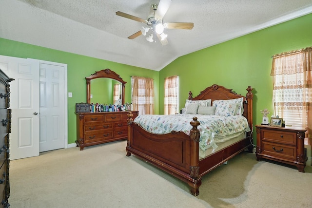 carpeted bedroom featuring a textured ceiling, a ceiling fan, and vaulted ceiling